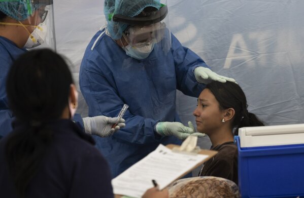 A young woman gets tested for COVID-19 at a health center in Salesiano park, in the Miguel Hidalgo district of Mexico City, Wednesday, July 15, 2020. (AP Photo/Marco Ugarte)