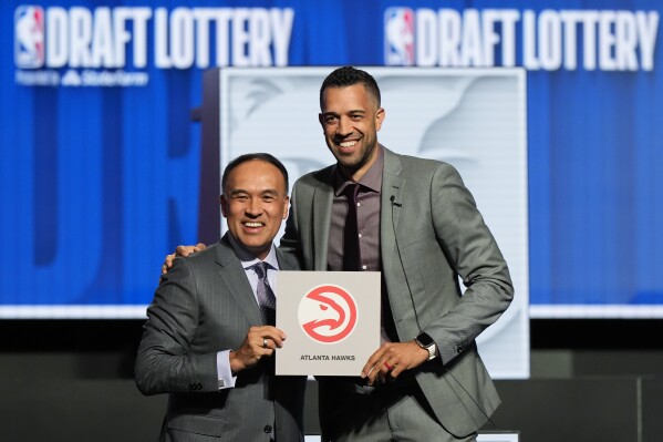 Atlanta Hawks general manager Landry Fields, right, and NBA Deputy Commissioner Mark Tatum pose for photos after Tatum announced that the Hawks had won the first pick in the NBA draft, during the draft lottery in Chicago, Sunday, May 12, 2024. (AP Photo/Nam Y. Huh)