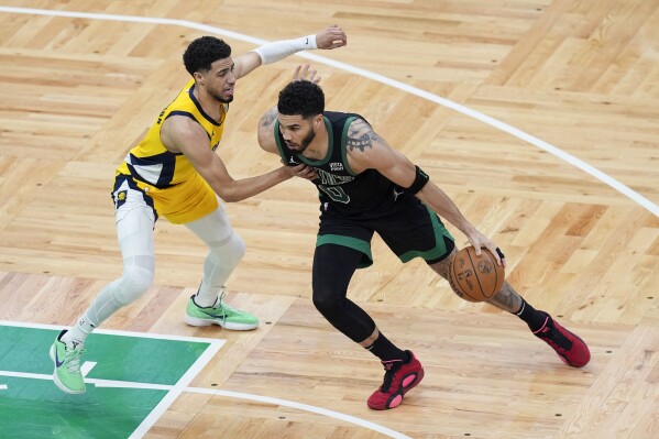 Boston Celtics forward Jayson Tatum (0) is defended by Indiana Pacers guard Tyrese Haliburton, left, during the first half of Game 2 of the NBA Eastern Conference basketball finals Thursday, May 23, 2024, in Boston. (AP Photo/Michael Dwyer)