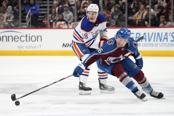 Colorado Avalanche right wing Mikko Rantanen, right, reaches out for the puck as Edmonton Oilers left wing Zach Hyman, left, defends in the third period of an NHL hockey game Sunday, Feb. 19, 2023, in Denver. (AP Photo/David Zalubowski)