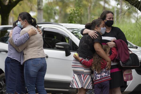 People embrace as they wait for information about missing relatives after a massive slab of rock broke away from a cliff and toppled onto pleasure boaters at Furnas reservoir on Saturday, killing at least seven people, near Capitolio city, Brazil, Sunday, Jan. 9, 2022. (AP Photo/Igor do Vale)