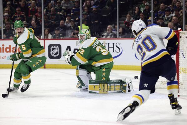 Minnesota Wild goaltender Filip Gustavsson (32) watches St. Louis Blues left wing Brandon Saad (20) shoot the puck during the first period of an NHL hockey game Sunday, Jan. 8, 2023, in St. Paul, Minn. (AP Photo/Stacy Bengs)