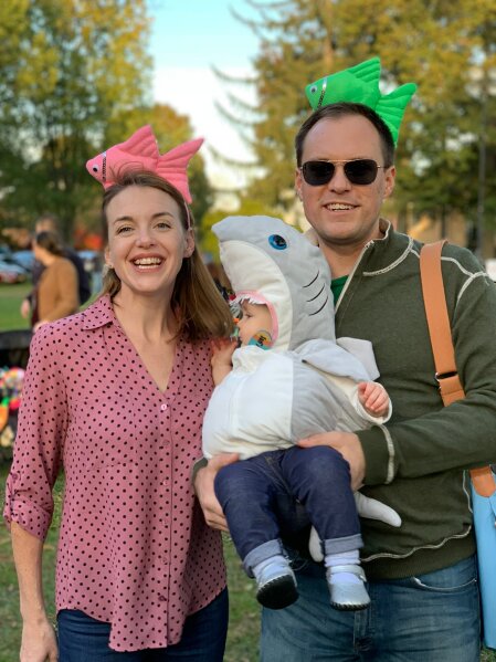 
              This image released by Jason Simms shows him with his wife Jillian and their daughter Fionnuala wearing a shark costume on the Town Green in Madison, Conn.  Fionnuala first heard the "Baby Shark" song when she was 8 months old. Her parents say it was one of the first things in life she directly expressed a preference for, so they picked it for her Halloween costume. (Jason Simms via AP)
            