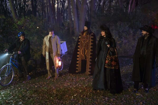 This image released by FX shows, from left, Harvey Guillén as Guillermo, Mark Proksch as Colin Robinson, Kayvan Novak as Nandor, Natasia Demetriou as Nadja and Matt Berry as Laszlo in a scene from "What We Do in the Shadows." The comedy series spun from Jemaine Clement and Taika Waititi’s mockumentary film returns for season two on Wednesday. (Russ Martin/FX via AP)