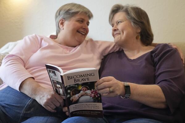 Sharon Bishop-Baldwin, left, and Mary Bishop-Baldwin, right, pose for a photo with the book that Sharon authored about their fight to be allowed to marry, in their home Tuesday, Nov. 29, 2022, in Broken Arrow, Okla. (AP Photo/Sue Ogrocki)