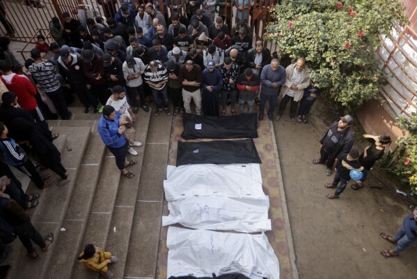 Palestinians pray near the wrapped bodies of relatives killed in the Israeli bombardment of the Gaza Strip, outside a morgue in Khan Younis on Wednesday, Dec. 27, 2023. (AP Photo/Mohammed Dahman)