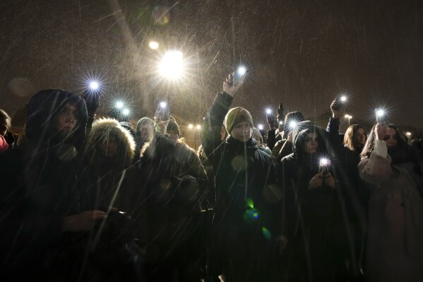 People wave their mobile phones with flashlights on as they pay their last respects to jailed Russian opposition leader Alexei Navalny at the Memorial to Victims of Political Repression in St. Petersburg, Russia on Friday, Feb. 16, 2024. (AP Photo/Dmitri Lovetsky)