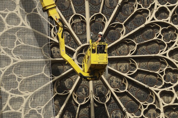 FILE - Workers fix a net to cover one of the iconic stained glass windows of the Notre Dame Cathedral in Paris, Sunday, April 21, 2019. The restoration of Notre Dame hits a milestone Friday, Dec. 8, 2023: one year until the cathedral reopens its huge doors to the public. (APPhoto/Francisco Seco, File)