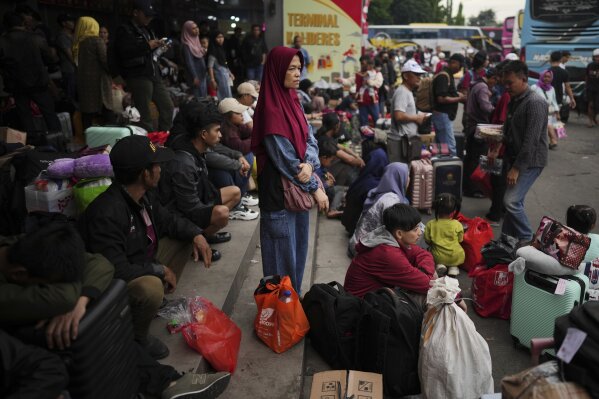 People wait for the bus that will bring them to their home towns during the mass exodus out of the the capital city ahead of Eid al-Fitr, the holiday marking the end of the Muslim fasting month, at Kalideres bus terminal in Jakarta, Indonesia, Friday, March 28, 2025. (AP Photo/Dita Alangkara)