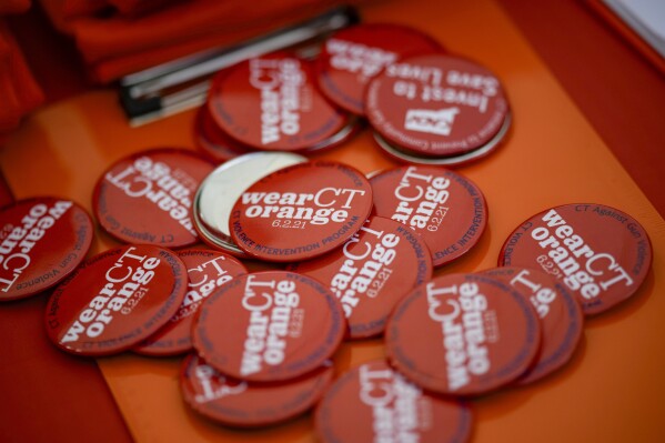 Des boutons étaient posés sur une table lors d'un rassemblement contre la violence armée le vendredi 7 juin 2024 à Newtown, Connecticut.  (Photo AP/Bryan Woolston)