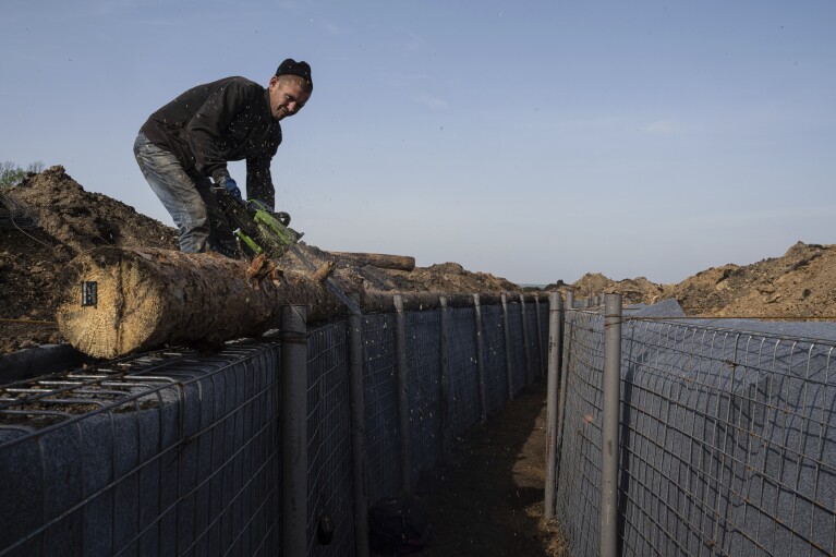 A worker constructs new defensive positions close to the Russian border in Kharkiv region, Ukraine, on Wednesday, April 17, 2024. (AP Photo/Evgeniy Maloletka)