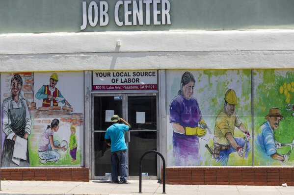 FILE - In this May 7, 2020, file photo, a person looks inside the closed doors of the Pasadena Community Job Center in Pasadena, Calif., during the coronavirus outbreak. While most Americans have weathered the pandemic financially, about 38 million say they are worse off now than before the outbreak began in the U.S. According to a new poll from Impact Genome and The Associated Press-NORC Center for Public Affairs Research 55% of Americans say their financial circumstances are about the same now as a year ago, and 30% say their finances have improved.    (AP Photo/Damian Dovarganes, File)