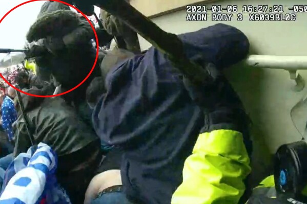 This image from police body-worn camera video, contained and annotated in the Justice Department's sentencing memorandum against Michael Joseph Foy, shows Foy swinging his hockey stick as he lunges at the police line, at the U.S. Capitol on Jan. 6, 2021, in Washington. Foy, a former military officer who assaulted police officers with a hockey stick and a sharp metal pole during the U.S. Capitol riot has been sentenced to more than three years in prison.(Department of Justice via AP)