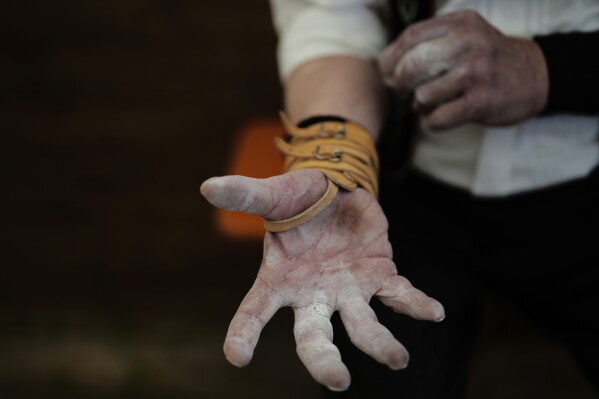 A competitor warms up for his bout while he try to pull the opponent over the table at the German Championships in Fingerhakeln or finger wrestling, in Pang, near Rosenheim, Germany, Sunday, April 27, 2025. (AP Photo/Matthias Schrader)