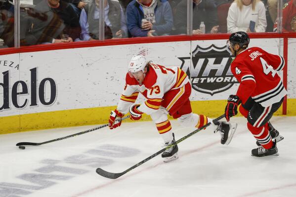 Calgary Flames right wing Tyler Toffoli (73) looks to pass the puck against Chicago Blackhawks defenseman Seth Jones (4) during the second period of an NHL hockey game, Monday, April 18, 2022, in Chicago. (AP Photo/Kamil Krzaczynski)