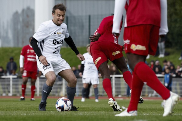 French President Emmanuel Macron controls the ball as he participates in the Varietes Club charity football match to benefit children in hospital, at the Bernard Giroux stadium in Plaisir, outside Paris, Wednesday, April 24, 2024. (Benoit Tessier/Pool via AP)