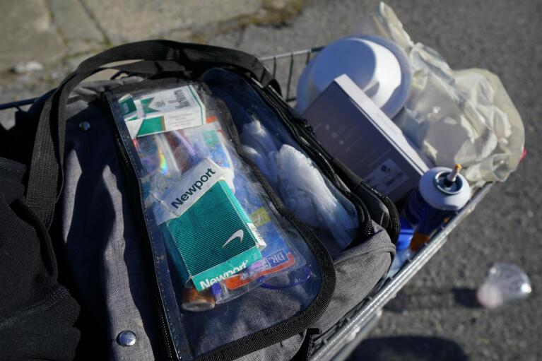 A patient's belongings are seen on a shopping cart as he is treated inside a Baltimore City Health Department RV, Monday, March 20, 2023, in Baltimore. The Baltimore City Health Department's harm reduction program uses the RV to address the opioid crisis, which includes expanding access to medication assisted treatment by deploying a team of medical staff to neighborhoods with high rates of substance abuse and offering buprenorphine prescriptions. (AP Photo/Julio Cortez)