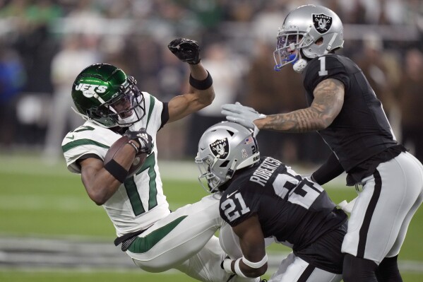 New York Jets wide receiver Garrett Wilson (17) is stopped by Las Vegas Raiders cornerback Amik Robertson (21) and safety Marcus Epps (1) after catching a pass during the first half of an NFL football game Sunday, Nov. 12, 2023, in Las Vegas. (AP Photo/John Locher)