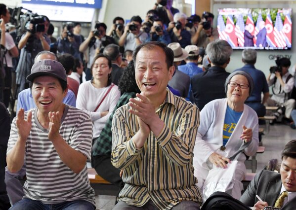 
              People celebrate as they watch a TV showing U.S. President Donald Trump meets with North Korean leader Kim Jong Un during a news program at Seoul Railway Station in Seoul, South Korea, Tuesday, June 12, 2018. (Kyodo News via AP)
            