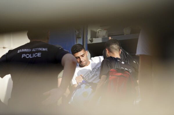 Egyptian shipwreck survivors enter a police station to be processed following their release from prison, in the town of Nafplio, about 136 kilometers (85 miles) southwest of Athens, Greece, Wednesday, May 22, 2024. A Greek court Monday dismissed a case against nine Egyptian defendants accused of causing a shipwreck off the southern coast of Greece last June that killed several hundred migrants travelling from Libya to Italy. The suspects had spent 11 months in pre-trial prison detention. (AP Photo/Elena Becatoros)