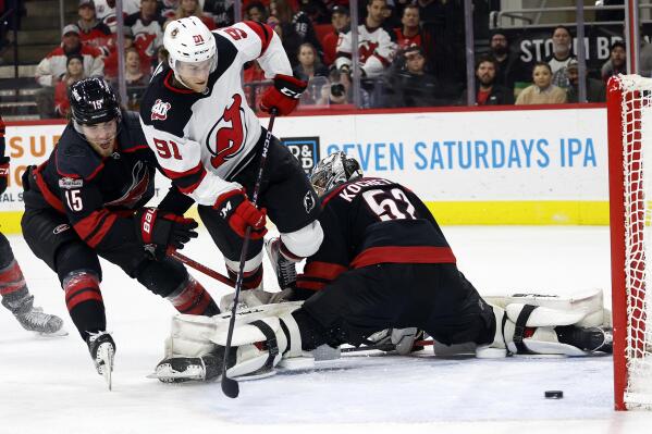 New Jersey Devils' Dawson Mercer (91) shoots the puck for a goal after driving between Carolina Hurricanes' Dylan Coghlan (15) and Pyotr Kochetkov (52) during the third period of an NHL hockey game in Raleigh, N.C., Tuesday, Jan. 10, 2023. (AP Photo/Karl B DeBlaker)