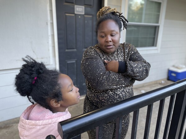 Tameka and her 8-year-old daughter talk on their porch in Atlanta on Dec. 5, 2023, about when she might start school. The little girl should be in second grade but has never attended school. Tameka's kids have essentially been out of school since COVID hit in March 2020. They have had a consistent place to live, but nearly everything else in their lives collapsed during the pandemic. (AP Photo/Bianca Vázquez Toness)
