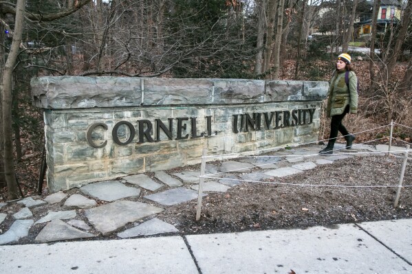 FILE - A woman walks by a Cornell University sign on the Ivy League school's campus in Ithaca, New York, on Jan. 14, 2022. Cornell University administrators dispatched campus police to a Jewish center after threatening statements appeared on a discussion board Sunday, Oct. 29, 2023. (AP Photo/Ted Shaffrey, File)