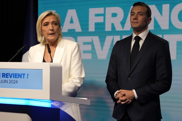 French far-right leader Marine Le Pen speaks as Jordan Bardella, president of the French far-right National Rally, listens at the party election night headquarters after French President Emanuel Macron announced he dissolves National Assembly and calls new legislative election after defeat in EU vote, Sunday, June 9, 2024 in Paris. First projected results from France put far-right National Rally party well ahead in EU elections, according to French opinion poll institutes. (AP Photo/Lewis Joly)