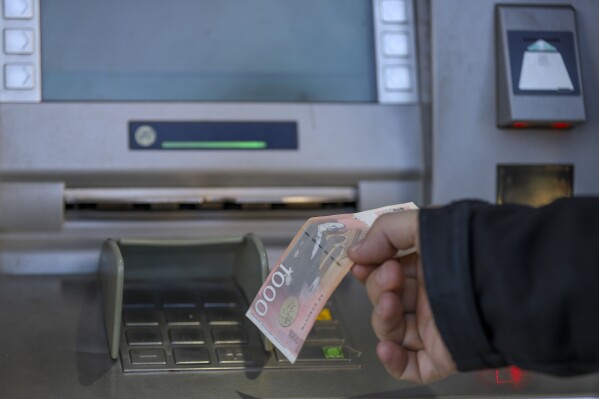 FILE - A man withdraws Serbian Dinars from a bank cash machine in northern Serb-dominated part of ethnically divided town of Mitrovica, Kosovo, on Jan. 31, 2024. The European Union on Tuesday, May 21, 2024, reprimanded Kosovo over the unilateral closure of six branches of a Serbia-licensed bank, saying the move would negatively impact the life of the ethnic Serb minority living in northern Kosovo and damage Kosovo-Serbia normalization talks. (AP Photo/Bojan Slavkovic)