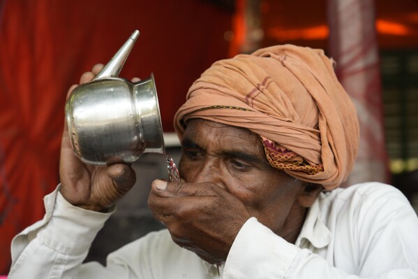 A man drinks water as severe heat grips Lucknow, India, Saturday, May 18, 2024. Swathes of northwest India sweltered under scorching temperatures on Saturday, with the capital New Delhi under a severe weather alert as extreme temperatures strike parts of the country. (AP Photo/Rajesh Kumar Singh)