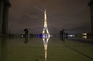 People stroll on the Trocadero square to watch the Eiffel Tower lightings, Friday, Dec. 11, 2020 in Paris. (AP Photo/Francois Mori)