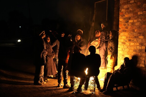 People huddle around a fire for warmth in the Angelo Informal Settlement in Boksburg, South Africa, on Thursday July 6, 2023. Police said a gas leak left multiple people dead including children. (AP Photo/Themba Hadebe)