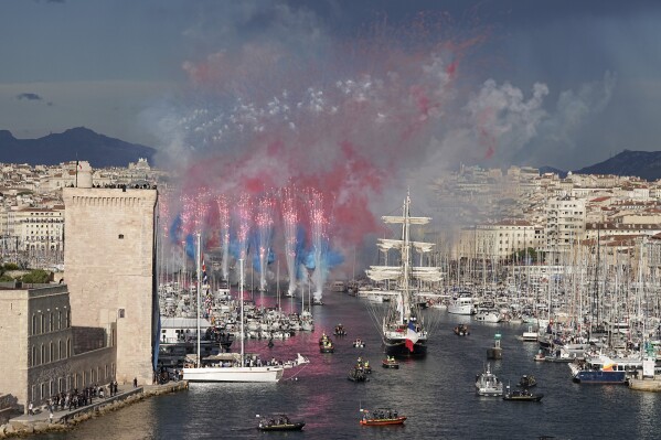 Fireworks go off as the Belem, the three-masted sailing ship bringing the Olympic flame from Greece, enters the Old Port in Marseille, southern France, Wednesday, May 8, 2024. (AP Photo/Laurent Cipriani)