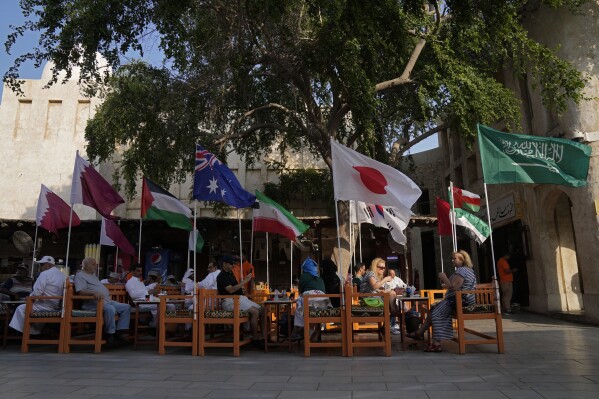 Foreign visitors spend time at a restaurant at Souk Waqif decorated with the flags of countries participating in the Asian Cup, a major international soccer tournament, in Doha, Qatar, Tuesday, Jan. 16, 2024. (AP Photo/Aijaz Rahi)