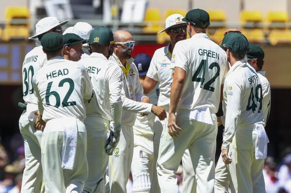 Australia's Nathan Lyon, centre, is congratulated by teammates after taking the wicket of England's Dawid Malan during day four of the first Ashes cricket test at the Gabba in Brisbane, Australia, Saturday, Dec. 11, 2021. (AP Photo/Tertius Pickard)