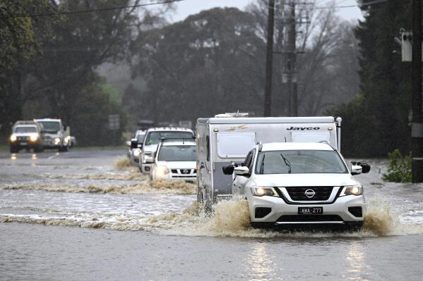 Cars slosh through a flooded road in Heathcote in Australia's Victoria State, Thursday, Oct. 13, 2022. Rivers across Australia's most populous states New South Wales and Victoria, as well as the island state of Tasmania were rising dangerously with catchments soaked by months of above-average rainfall. (James Ross/AAP Image via AP)