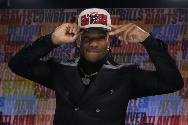 Texas running back Bijan Robinson puts on a hat after being chosen by the Atlanta Falcons with the eighth overall pick during the first round of the NFL football draft, Thursday, April 27, 2023, in Kansas City, Mo. (AP Photo/John Locher)