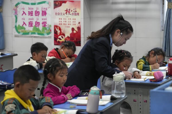 A teacher helps a student to write alphabets in a first-grade class at the Shangri-La Key Boarding School during a media-organized tour in Dabpa county, Kardze Prefecture, Sichuan province, China on Sept. 5, 2023. A government official from China's Tibetan region on Friday, Nov. 10, 2023 rejected allegations of forced assimilation and curbs on religious freedom, while stressing that Tibetan Buddhism should adapt to the Chinese context. (AP Photo/Andy Wong)