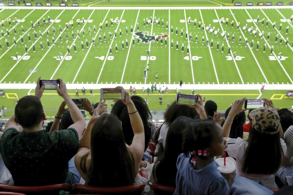 Fans use phones to record the Mississippi Valley State University marching band from the upper decks during the 2023 National Battle of the Bands, a showcase for HBCU marching bands, held at NRG Stadium, Saturday, Aug. 26, 2023, in Houston. (AP Photo/Michael Wyke)