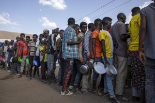 Tigrayan refugees wait in line to revive food from Muslim Aid at Hamdeyat Transition Center near the Sudan-Ethiopia border, eastern Sudan, Wednesday, March 24, 2021. (AP Photo/Nariman El-Mofty)