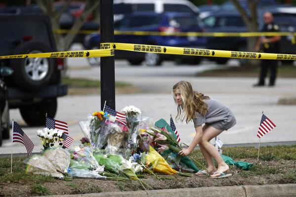 FILE - A girl leaves flowers at a makeshift memorial at the edge of a police cordon in front of a municipal building that was the scene of a shooting in Virginia Beach, Va., June 1, 2019. According to a letter dated Wednesday, Dec. 14, 2022, Virginia's attorney general has lambasted a state commission that is investigating a 2019 mass shooting in Virginia Beach, citing the panel's “overall dysfunction” and the resignation of nearly half its members. (AP Photo/Patrick Semansky, File)