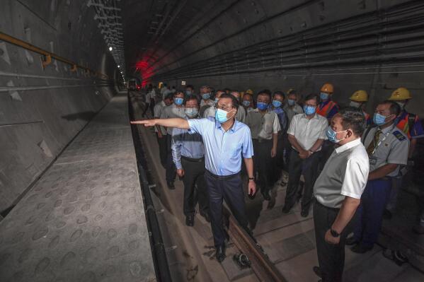 In this Aug. 18, 2021, photo released by Xinhua News Agency, Chinese Premier Li Keqiang, left, wearing a face mask, visits the tunnel of subway line 5 in Zhengzhou city in central China's Henan province. Li vowed to hold officials accountable over mistakes during recent floods that led to the deaths of hundreds of people in a major provincial capital, including 14 who were trapped when the city’s subway system was inundated. (Rao Aimin/Xinhua via AP)