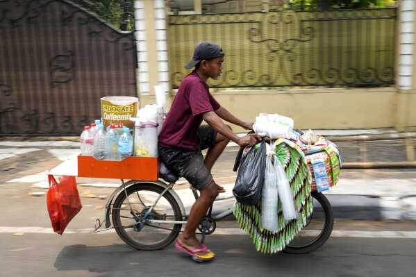 A snack and drink vendor carries his wares on a bike in Jakarta, Indonesia Tuesday, Oct. 24, 2023. Indonesia 鈥� the biggest sugar importer last year, according to the United States Department of Agriculture 鈥� has cut back on imports. (AP Photo/Tatan Syuflana)