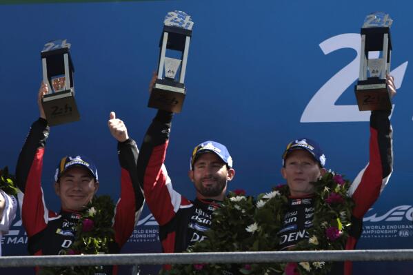 Toyota Gazoo Racing GR010 Hybrid drivers Britain's Mike Conway, right, Japan's Kamui Kobayashi, left, and Argentina's Jose Maria Lopez hold their trophies after finishing second in the 24-hHour Le Mans endurance race Le Mans, western France, Sunday June 12, 2022. (AP Photo/Jeremias Gonzalez)