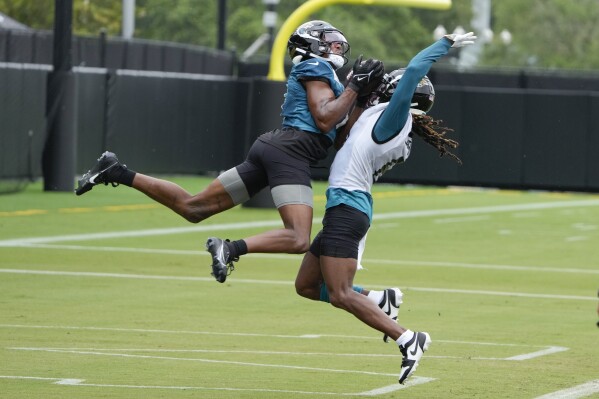 Jacksonville Jaguars wide receiver Zay Jones, left, leaps and makes a catch over cornerback Chris Claybrooks as he tries to defend during a practice at the NFL football team's training camp, Monday, July 31, 2023, in Jacksonville, Fla. (AP Photo/John Raoux)