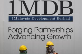 FILE - Construction workers chat in front of a billboard for state investment fund 1 Malaysia Development Berhad (1MDB) at the fund's flagship Tun Razak Exchange development in Kuala Lumpur, Malaysia, May 14, 2015. Swiss prosecutors on Tuesday, April 25, 2023 say they have indicted two managers of a Saudi oil exploration company as part of a years-long investigation of a case linked to a Malaysian sovereign wealth fund. The office of the Swiss attorney general said the two managers at PetroSaudi are accused of trying to enrich themselves and others by misappropriating at least $1.8 billion transferred to the 1Malaysia Development Berhad state fund, known as 1MDB. (AP Photo/Joshua Paul, File)