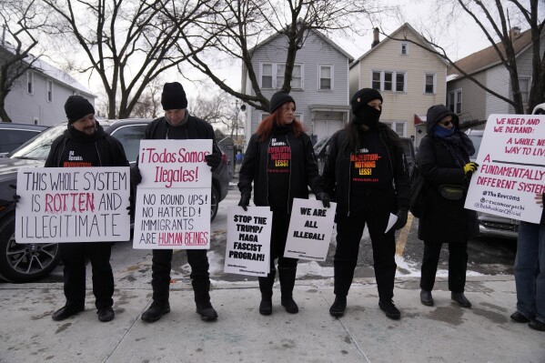 Activists with Revcom Corps Chicago hold signs outside of Hamline Elementary School after federal agents were turned away on Jan. 24, 2025, in Chicago. (AP Photo/Erin Hooley, file)