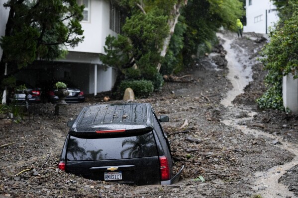 An SUV sits buried by a mudslide, Monday, Feb. 5, 2024, in the Beverly Crest area of Los Angeles. A storm of historic proportions unleashed record levels of rain over parts of Los Angeles on Monday, endangering the city's large homeless population, sending mud and boulders down hillsides dotted with multimillion-dollar homes and knocking out power for more than a million people in California. (AP Photo/Marcio Jose Sanchez)