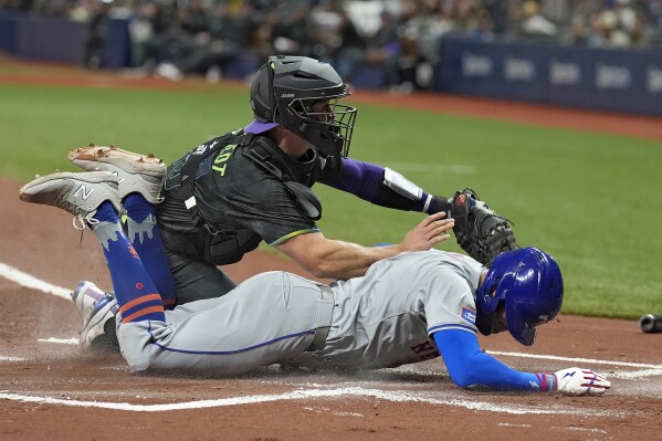 New York Mets' Brandon Nimmo slides into home plate under the tag by Tampa Bay Rays catcher Ben Rortvedt during the first inning of a baseball game Saturday, May 4, 2024, in St. Petersburg, Fla. Nimmo scored on an RBI single by Starling Marte. (AP Photo/Chris O'Meara)
