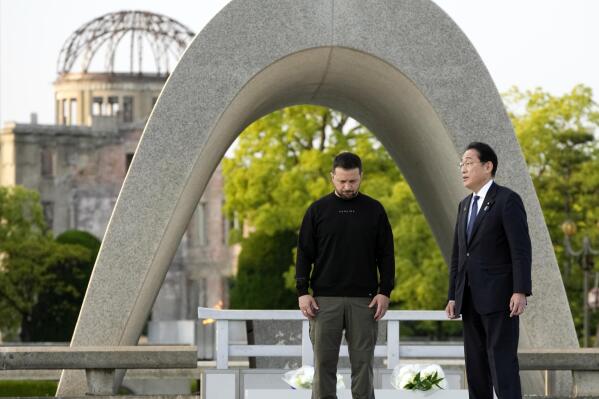 Ukrainian President Volodymyr Zelenskyy, left, and Japanese Prime Minister Fumio Kishida have a talk after laying flowers in front of the Cenotaph for the Victims of the Atomic Bomb at the Hiroshima Peace Memorial Park after he was invited to the Group of Seven (G7) nations' summit in Hiroshima, western Japan Sunday, May 21, 2023. The Atomic Bomb Dome is seen in the background. (AP Photo/Eugene Hoshiko, Pool)